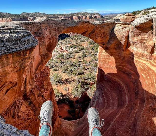 Hiker sits on top of the Cedar Tree Arch Overlook in Rattlesnake Arches